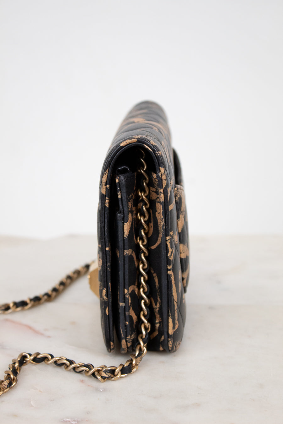 Black handbag with gold chain strap on a white background