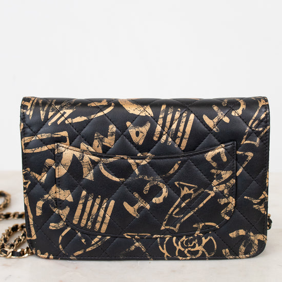 Black quilted handbag with gold lettering on a white marble surface