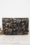 Black quilted handbag with gold lettering on a white marble surface