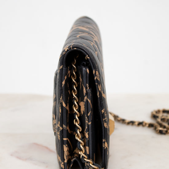 Black handbag with gold chain strap on a marble surface