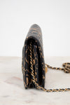 Black handbag with gold chain strap on a marble surface