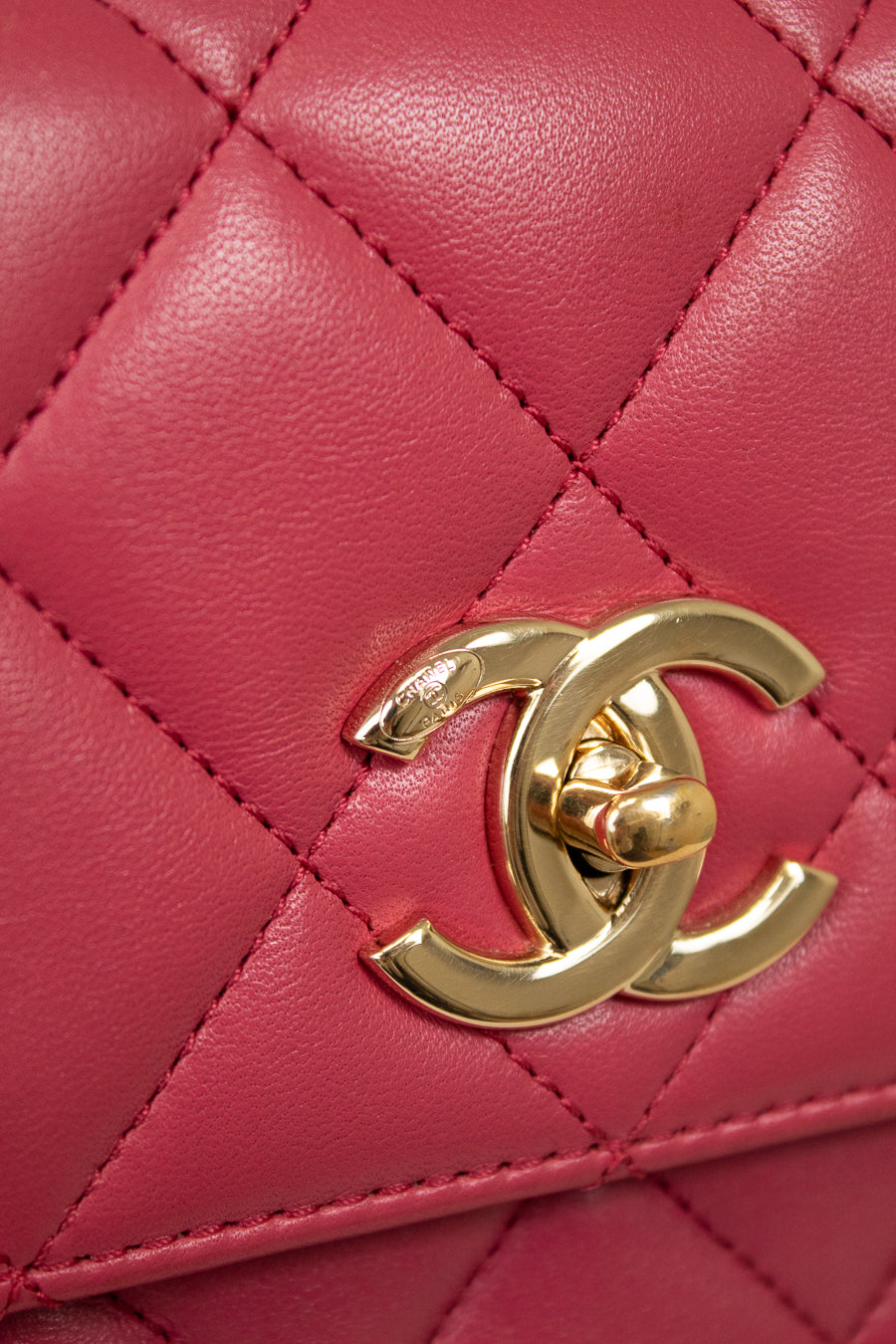 Close-up of a pink quilted handbag with a gold Chanel logo.