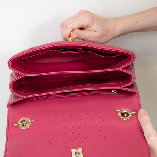 Pink Chanel handbag held open by a hand on a light background