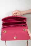 Pink Chanel handbag held open by a hand on a light background