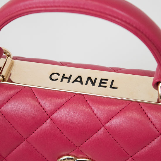Close-up of a pink Chanel handbag with gold hardware on a light gray background