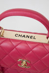 Close-up of a pink Chanel handbag with gold hardware on a light gray background