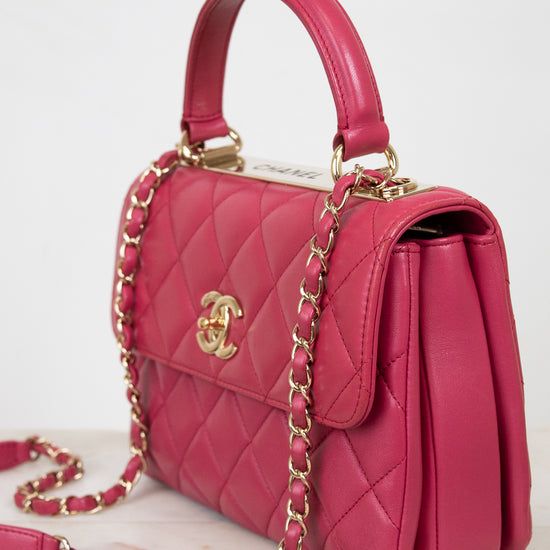 Pink quilted handbag with gold chain and hardware on a light background