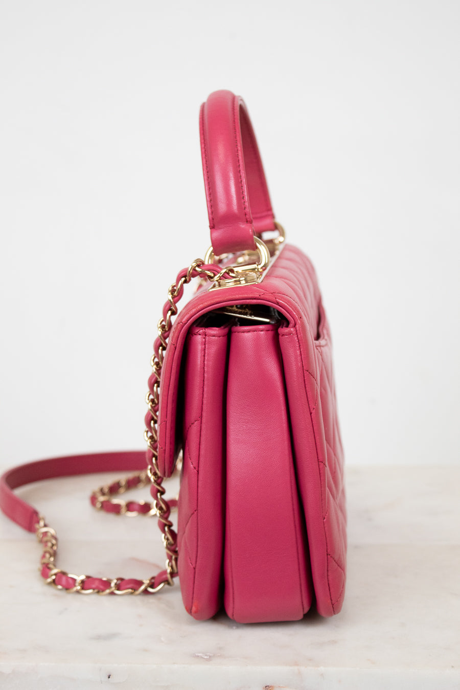 Pink handbag with gold chain on a white background