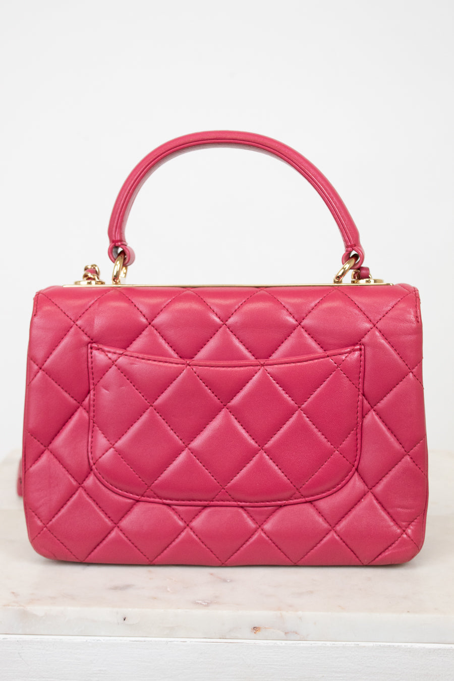 Pink quilted handbag on a white background