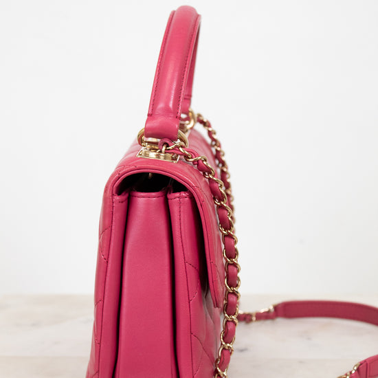 Pink handbag with gold chain strap on a light background