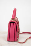 Pink handbag with gold chain strap on a light background
