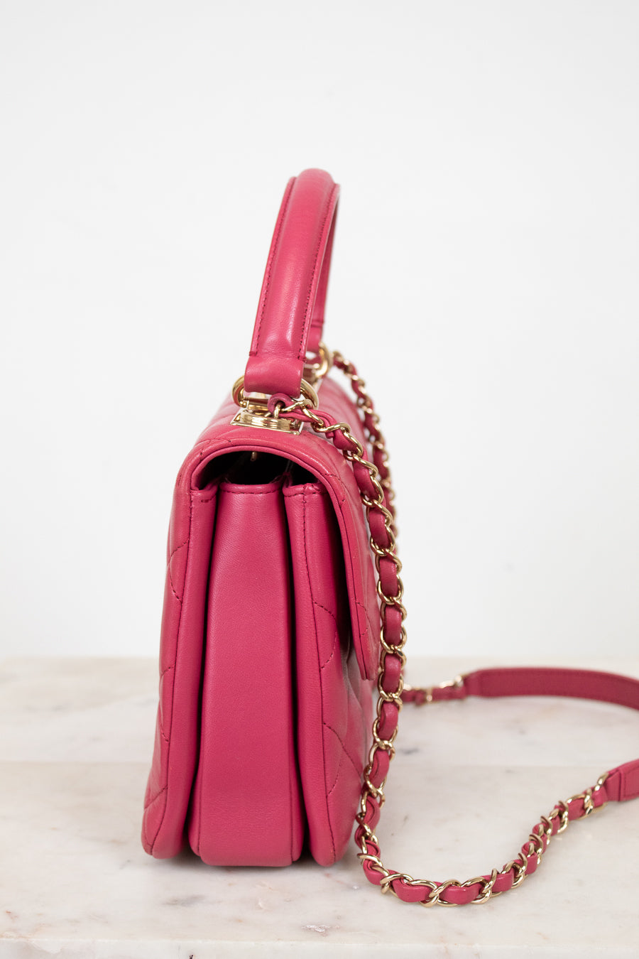 Pink handbag with gold chain strap on a light background
