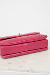 Pink quilted handbag on a light marble surface