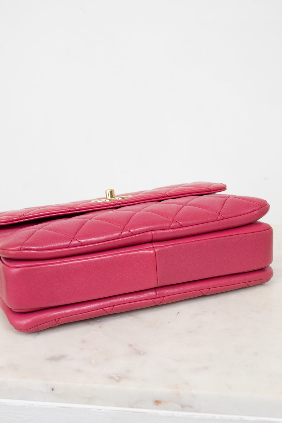 Pink quilted handbag on a light marble surface