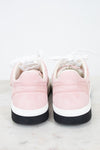 A pair of low-top sneakers shown from the back, featuring light pink suede uppers, white laces, a white midsole, and a black rubber outsole, set against a clean white background.