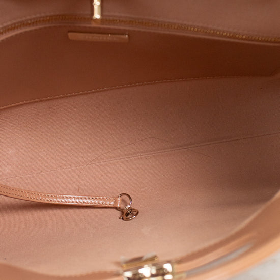 Close-up of the interior of a tan leather handbag, showing the lining, zipper track, and gold-tone hardware against a light surface.