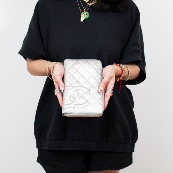 Person holding a white quilted handbag with a visible brand logo against a plain background