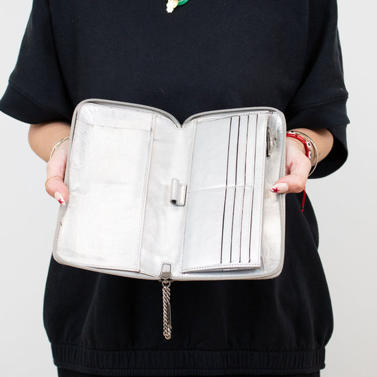Person holding a silver jewelry organizer against a white background