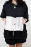 Person holding a silver jewelry organizer against a white background