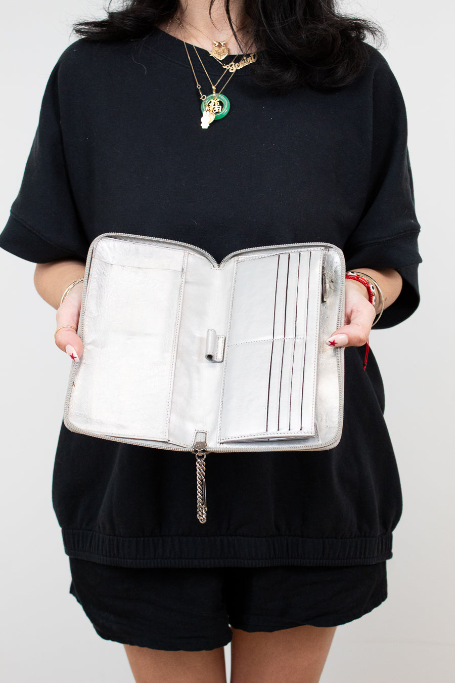 Person holding a silver jewelry organizer against a white background