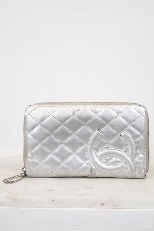 Silver quilted wallet with a brand logo on a white background