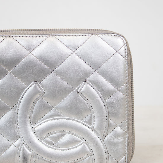 Silver quilted wallet with a brand logo on a white background
