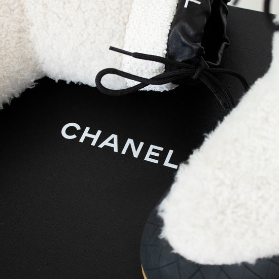 Black Chanel shoes with white fur lining on a black background