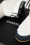 Black Chanel shoes with white fur lining on a black background