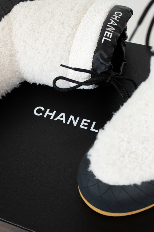 Black Chanel shoes with white fur lining on a black background