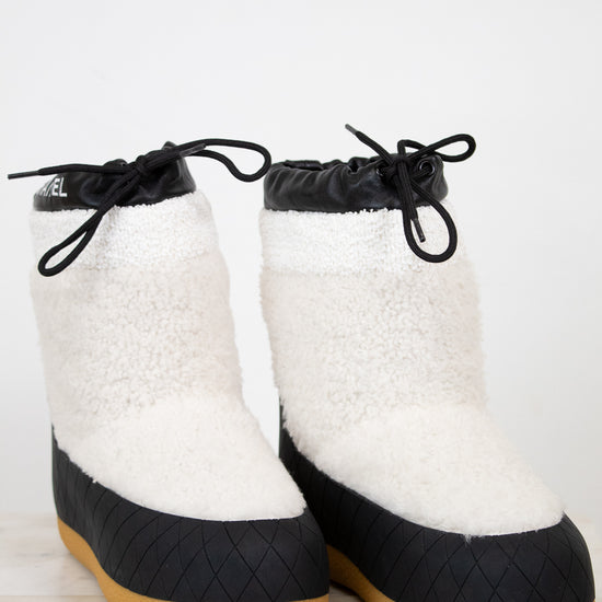 White and black quilted boots with brown soles on a light background