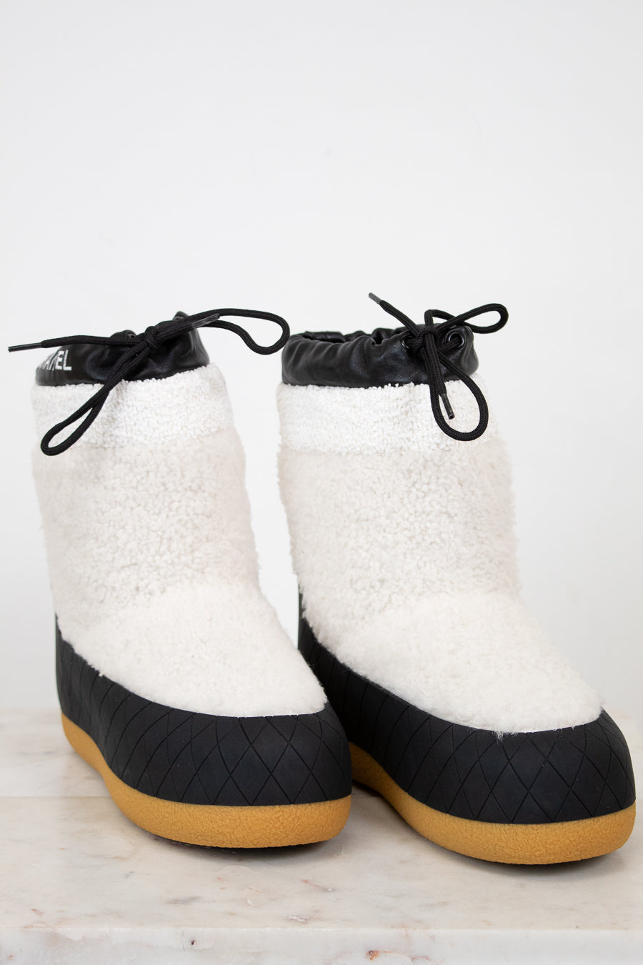 White and black quilted boots with brown soles on a light background