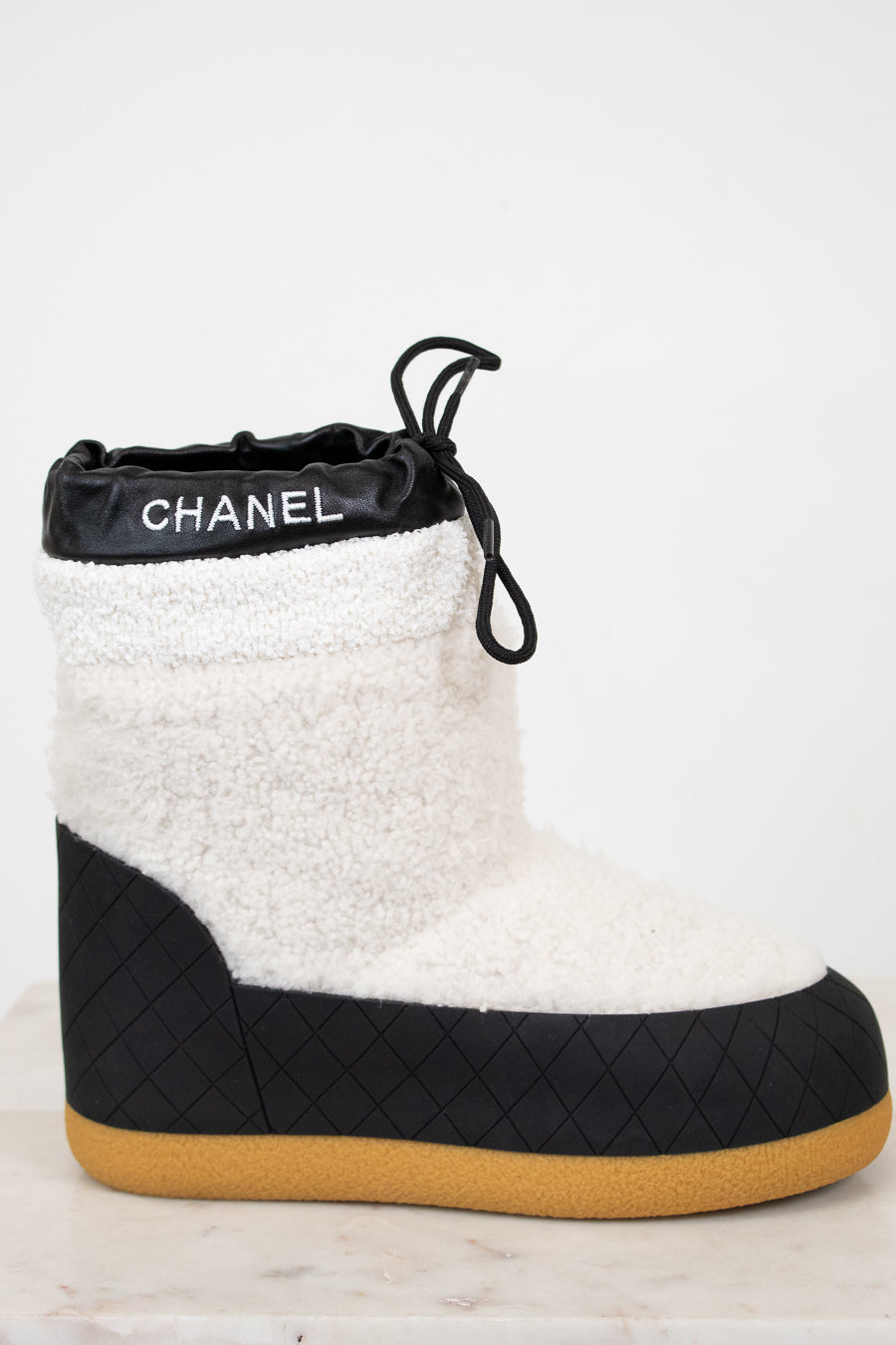 Chanel black and white quilted boot with tan sole on a light background