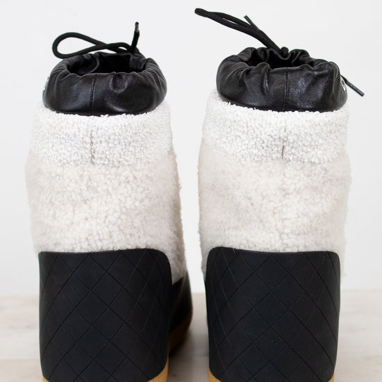 Pair of black and white shoes with quilted design on a light background