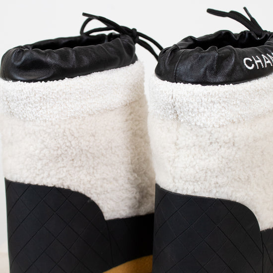 Pair of black and white quilted snow boots with tan soles on a light background