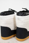 Pair of black and white quilted snow boots with tan soles on a light background