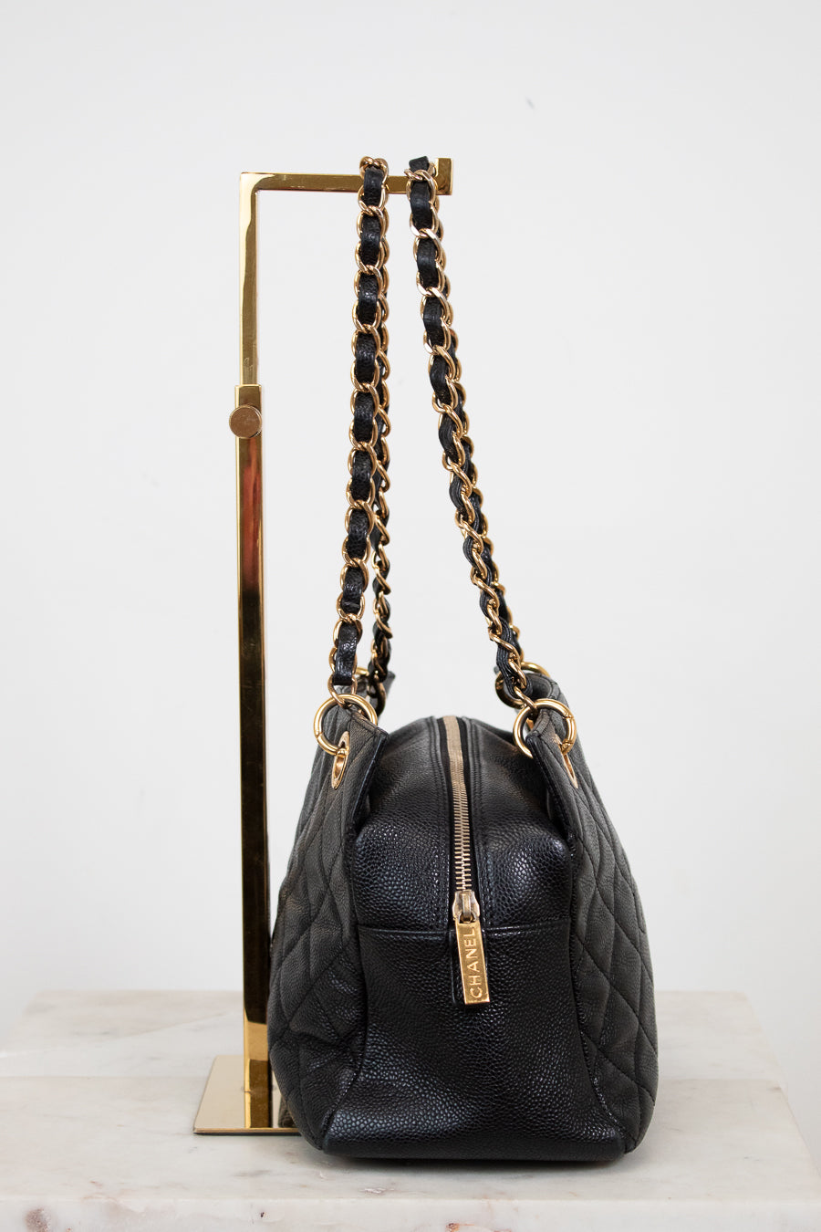Black handbag with gold chain strap on a white background