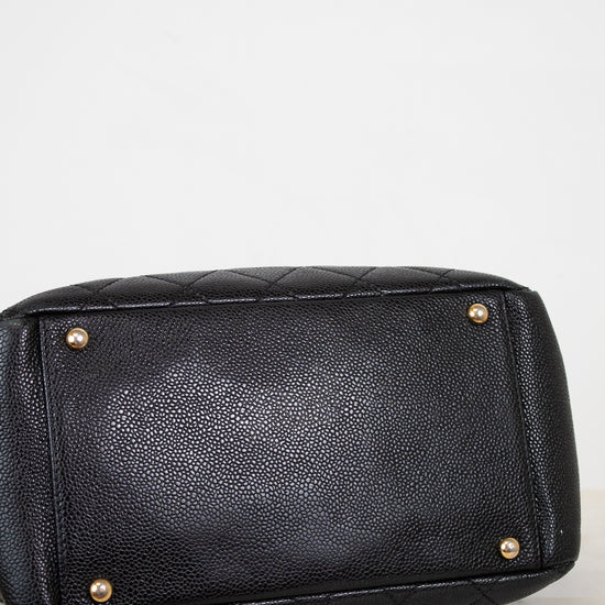 Black quilted handbag with gold-tone hardware on a light gray background