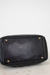 Black quilted handbag with gold-tone hardware on a light gray background