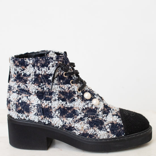 A black and white tweed ankle boot featuring black lace up detailing , silver tone eyelets decorative white pearl buttons, with black leather toe caps , and a chunky low block heel with black rubber sole.