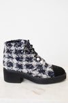 A black and white tweed ankle boot featuring black lace up detailing , silver tone eyelets decorative white pearl buttons, with black leather toe caps , and a chunky low block heel with black rubber sole.