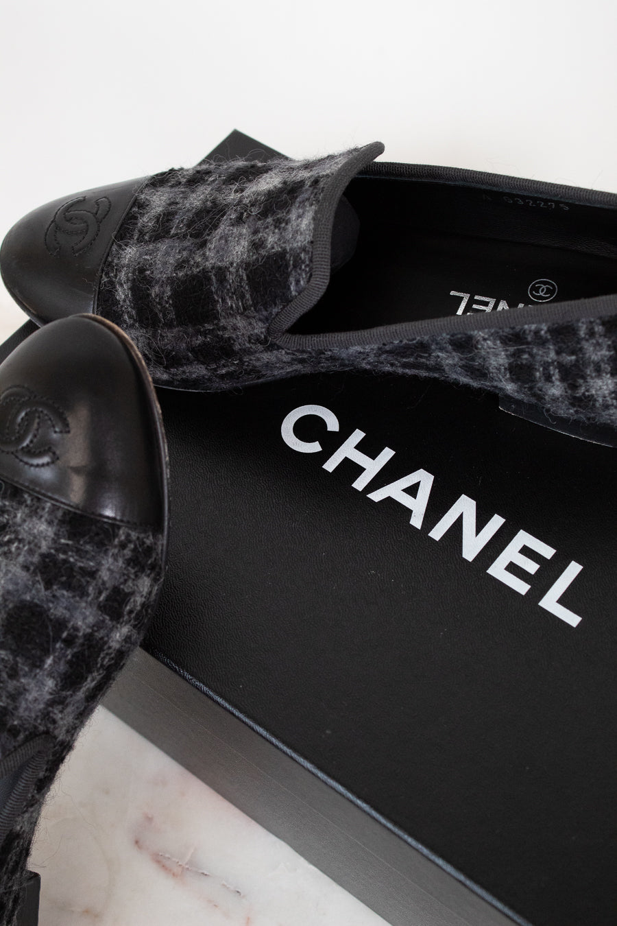 Black tweed Chanel shoes on a white background