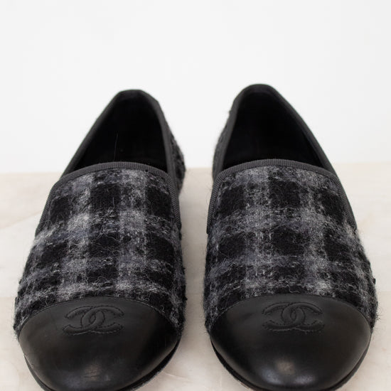 Pair of black and gray checkered tweed Chanel loafers on a white background