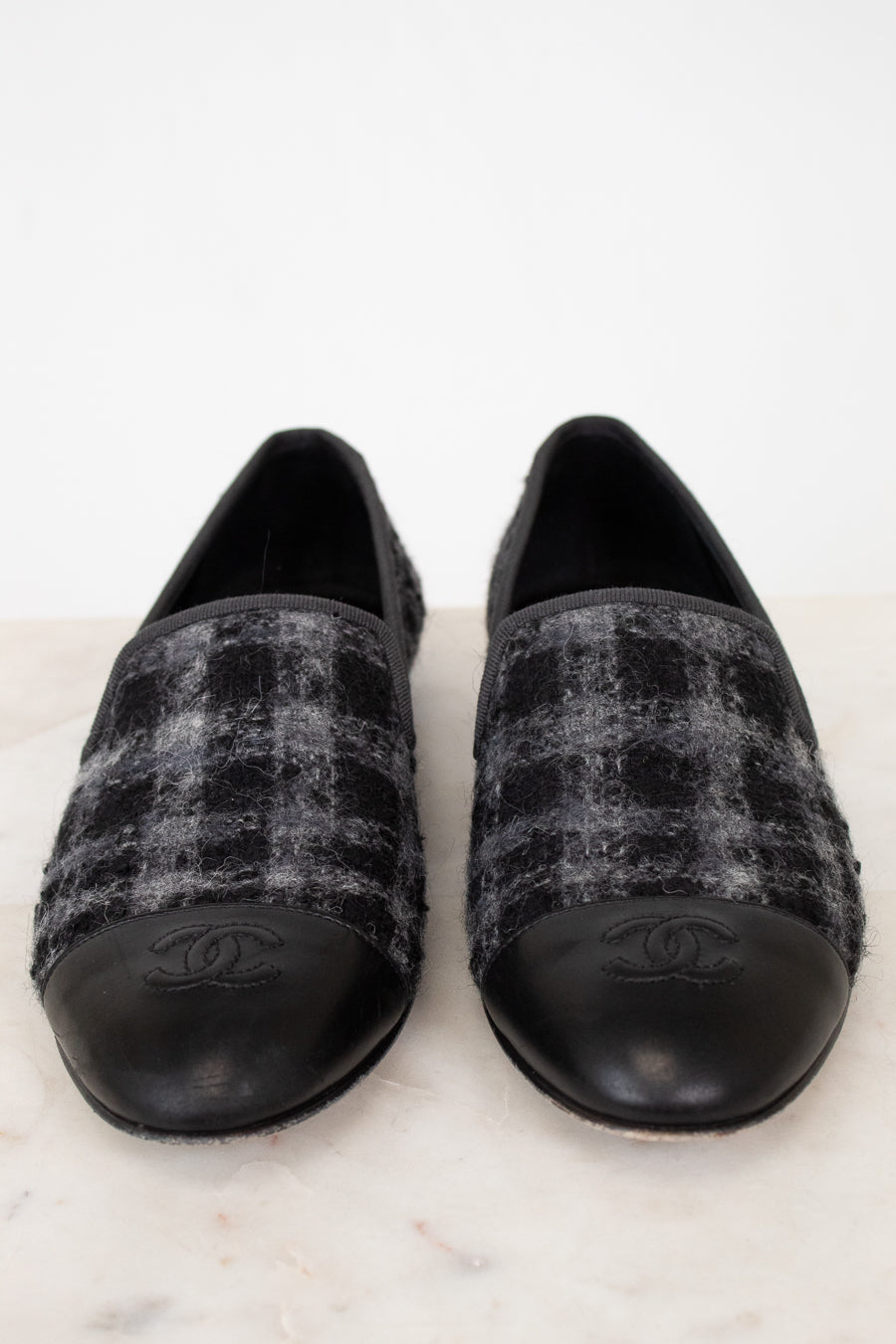 Pair of black and gray checkered tweed Chanel loafers on a white background