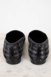 Pair of black and gray checkered tweed slippers on a white marble surface