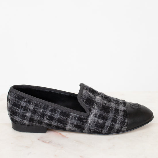 Black and gray checkered tweed loafer on a white marble surface