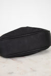 A black satin pouch bag with black leather piping, resting on a white marble surface against a white background.