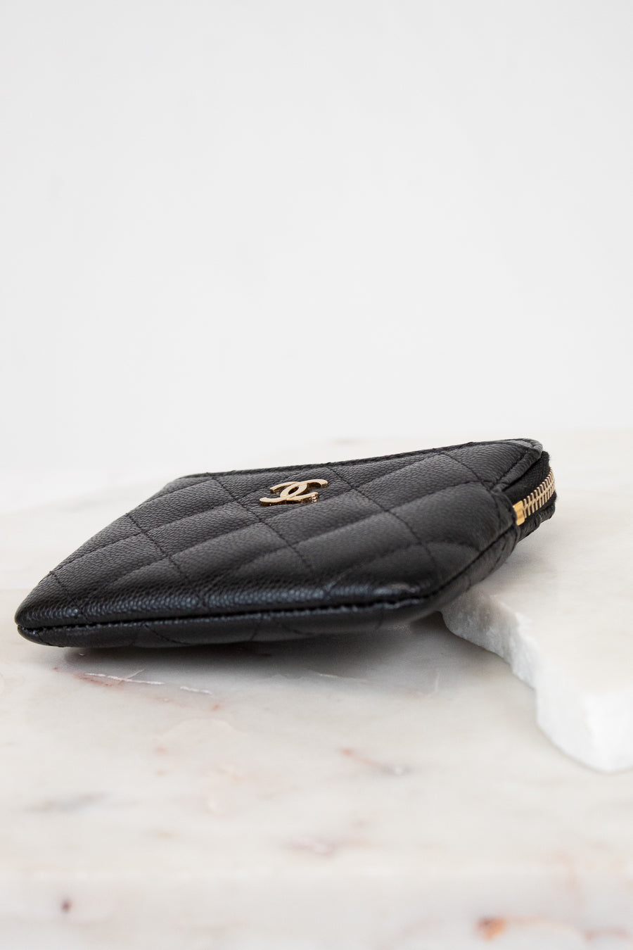 Black quilted wallet with gold logo on a white background