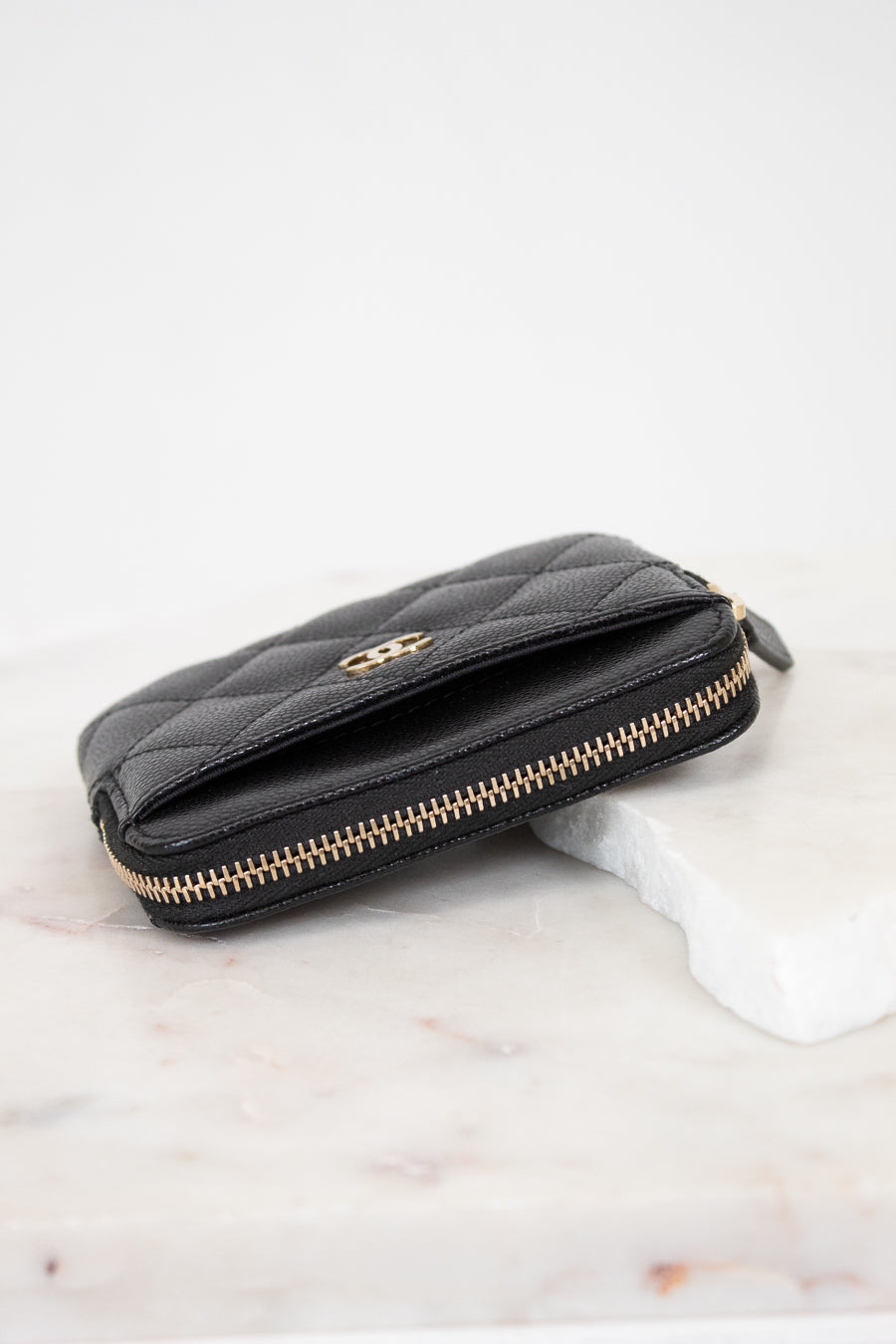Black quilted wallet with gold logo on a white background