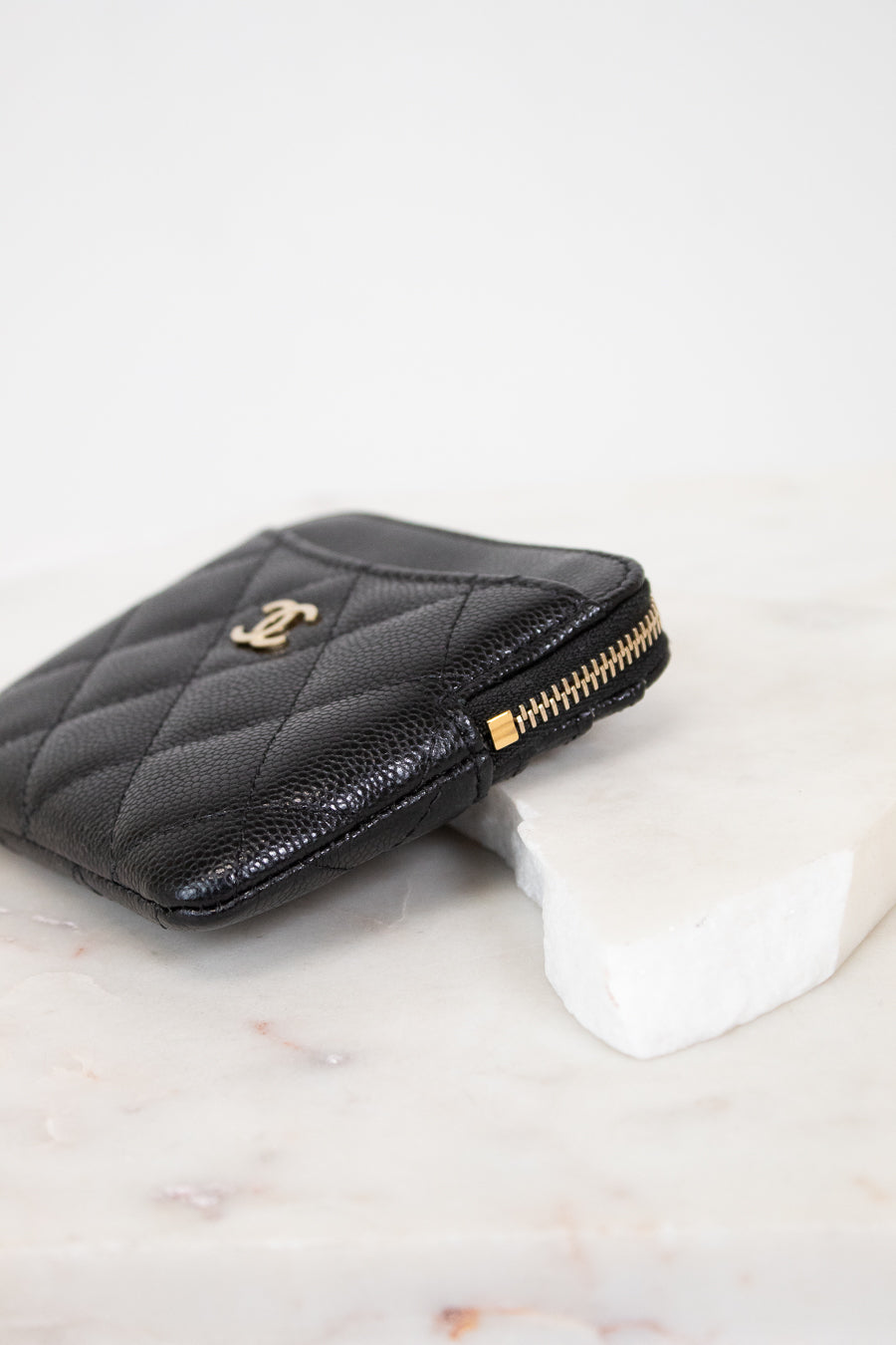 Black quilted wallet with gold logo on a white background