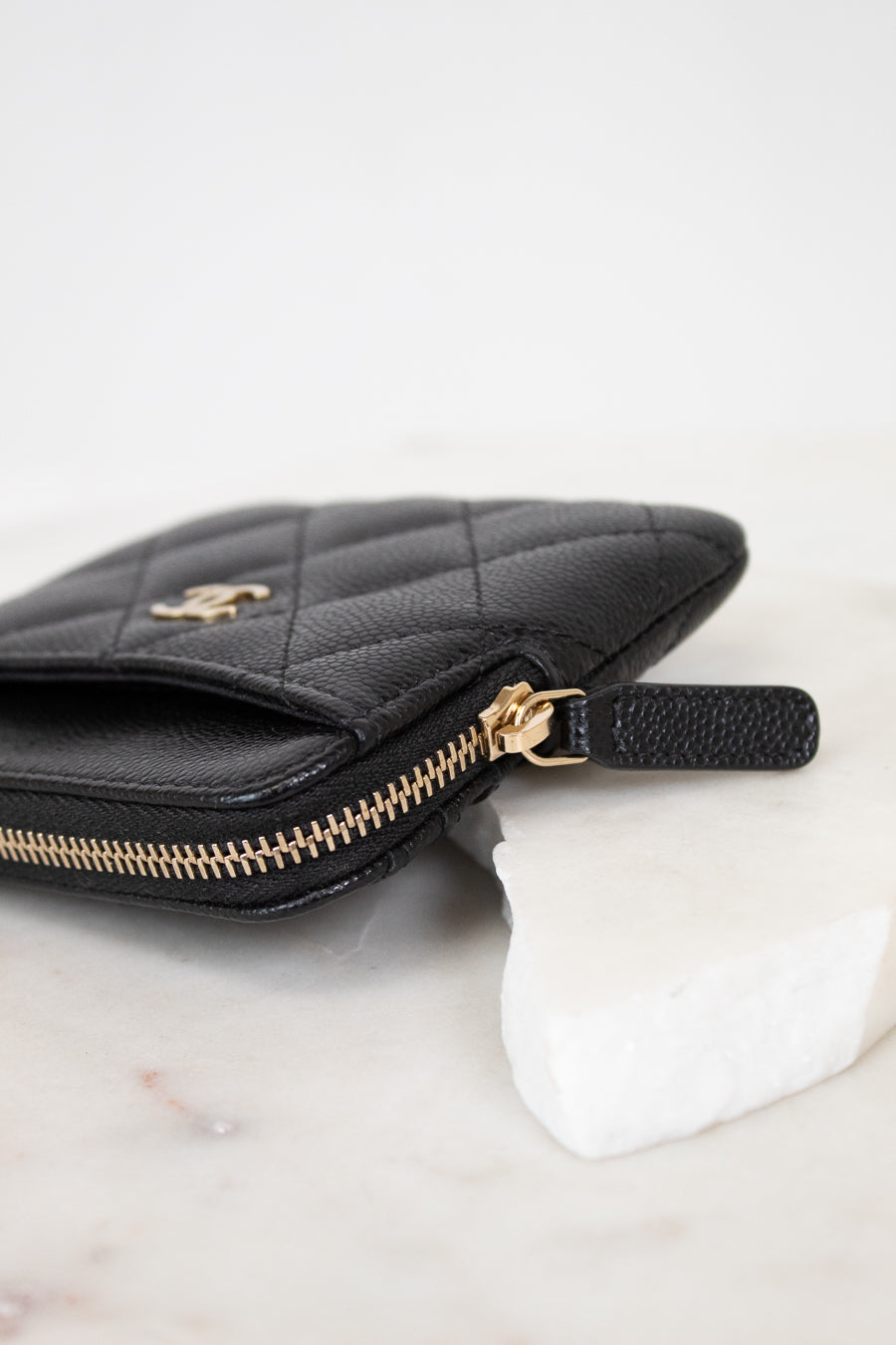 Black quilted wallet with gold logo on a white background